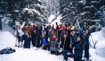 Group of people posing with ski poles in a snowy forest.