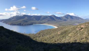 Aerial view of Wineglass Bay with clear blue waters and lush surrounding mountains.