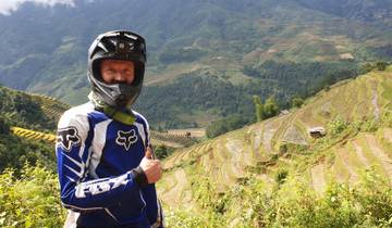 Motorcyclist posing against terraced fields.