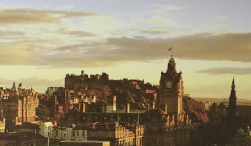 A cityscape at sunset with historic and modern architecture.