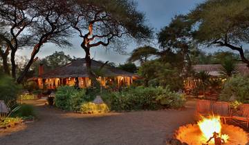 Lodge at dusk with fire pit and chairs.