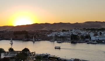 Sunset over a river with boats and buildings.