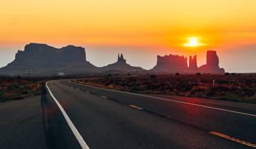 Sunset view over road leading to rock formations.