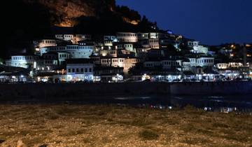 City at night with illuminated historic buildings.