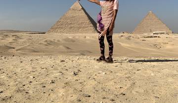 Person standing in front of the pyramids in Giza.