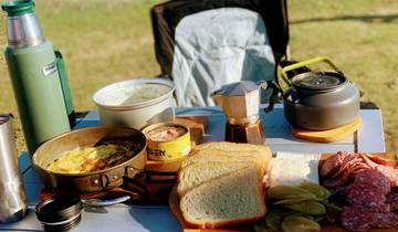 Outdoor picnic setup with various foods and drinks on a table.