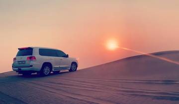 SUV on a sand dune with a sunset in the background
