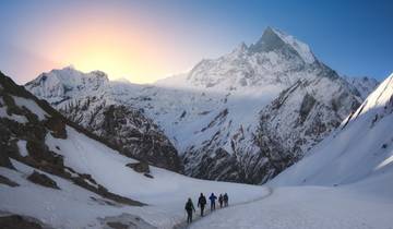 Group hiking through snowy mountain landscape at sunrise.