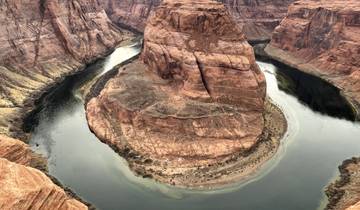 Aerial view of a river winding around a rock formation in a canyon.