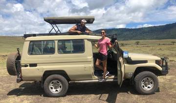 Couple standing by a safari jeep enjoying the scenery.