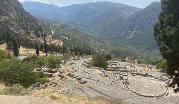 Ruins of an ancient theater with mountainous backdrop.