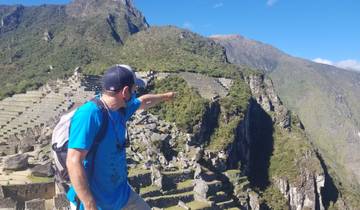 Person pointing towards ancient terraces in a mountain setting.
