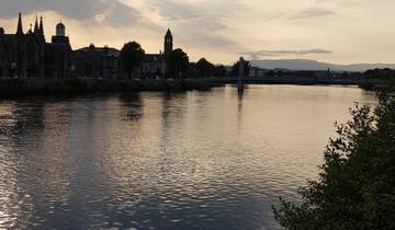River view at sunset with a bridge and cityscape.