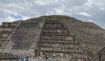 Large stone pyramid with tourists climbing the steps.