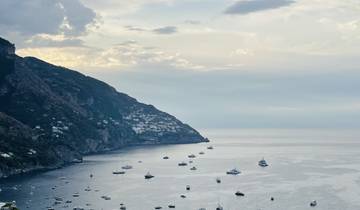 Scenic coastal view with boats on the water and hills.