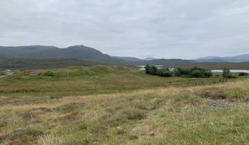 Rolling green hills with distant mountains and small lakes.