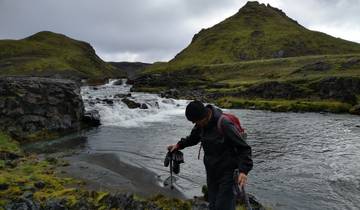 Person walking by a river in a mountainous landscape in Iceland.