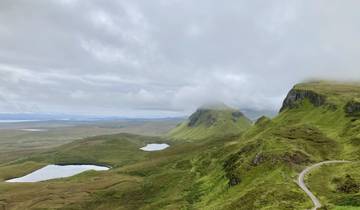Green rolling hills with small lakes under a cloudy sky.