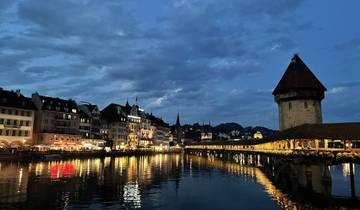 Night view of a city with water reflections and a stone tower.