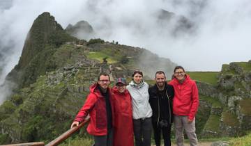 Group of people in front of Machu Picchu with misty clouds.