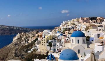 White buildings with blue domes overlooking the Aegean Sea.
