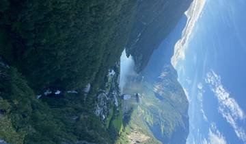A scenic view of a fjord with green mountains and a clear blue waterway.