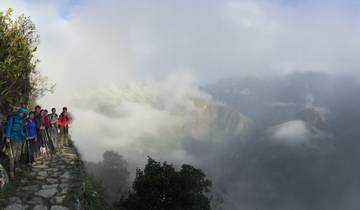 Group of trekkers on a mountain path shrouded in mist.