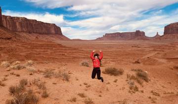 Person jumping with Monument Valley landscape in the background.