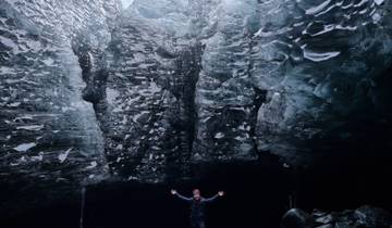 Man standing in a large icy cave.