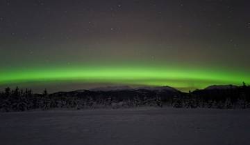 Aurora Borealis over a snowy mountain landscape at night.