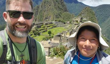 Two people smiling with the ruins of Machu Picchu in the background.
