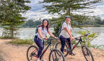 Two women biking along a river.