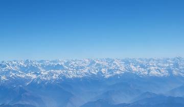 A vast mountain range covered in snow under a clear sky.