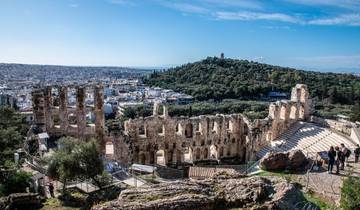 Ancient amphitheater overlooking a cityscape and green hills.