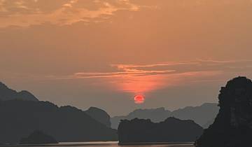 Stunning sunset over calm waters with dramatic clouds and distant cliffs.
