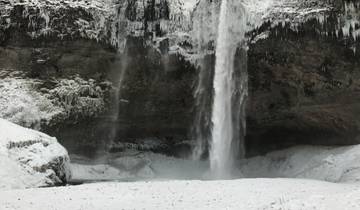 Frozen waterfall surrounded by snow.