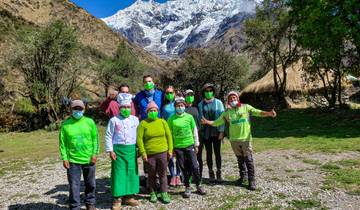 Group posing with masks in front of snow-capped mountains.