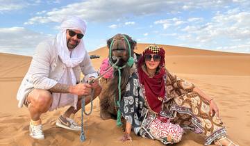Two people posing with a camel in the desert