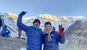 Two men in winter clothing with snowy mountains in the background.