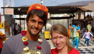 Two people wearing traditional garlands and tilak on their foreheads.
