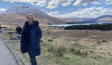 Person posing in front of scenic mountainous landscape.