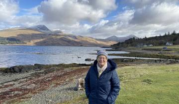 Person standing by a scenic lakeside view.