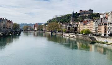 Scenic view of a river running through a city with a hilltop church in the background.
