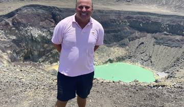 Man standing at the edge of a volcanic crater lake.