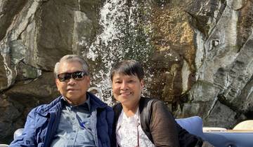 Couple sitting near a waterfall with rocky backdrop.