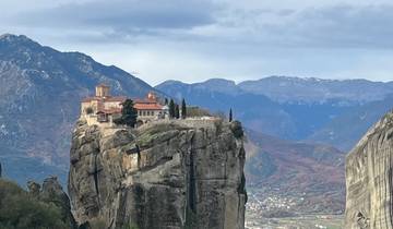 Cliff with a monastery built on top, with distant view of valley.