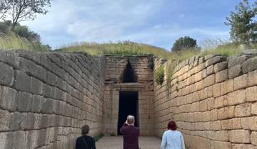 Three people walking towards an ancient tomb entrance.