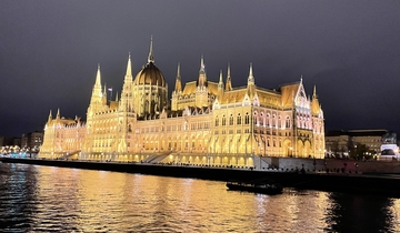 A grand, illuminated building reflected in a body of water at night.