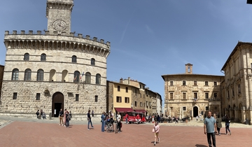A town square with historical buildings and tourists walking around.