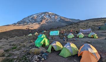 Campsite with colorful tents and a mountain in the background.